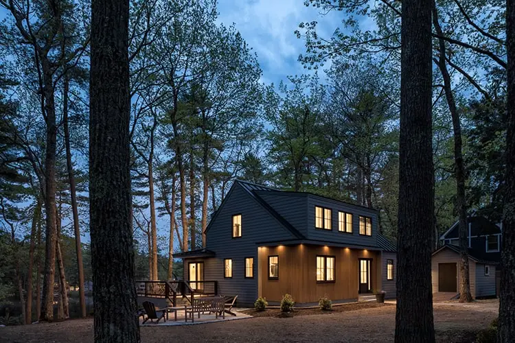 Lake house lit at dusk through the trees – Lake House project, Windham, Maine