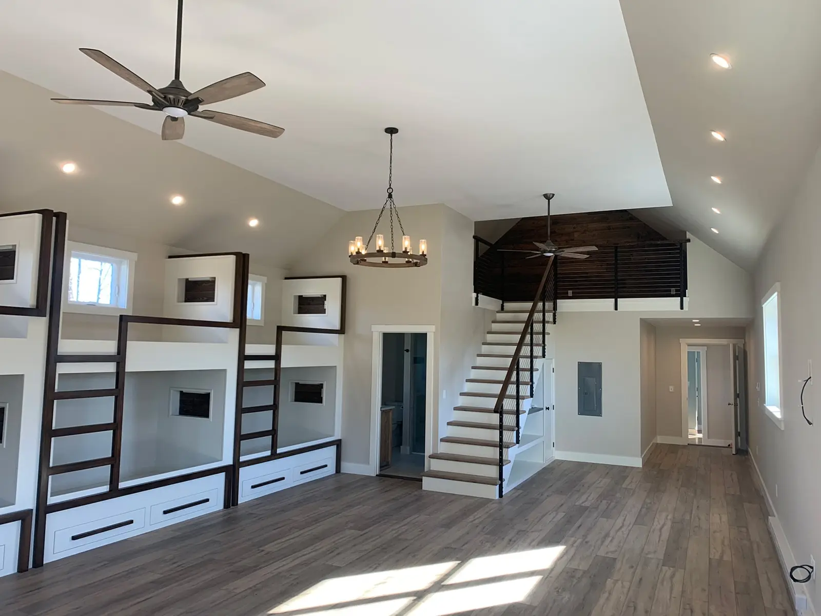 Renovated bunk room with built-in beds and open staircase by Codere Construction